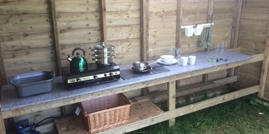 Covered kitchen area with cooking stove pots, pans and crockery