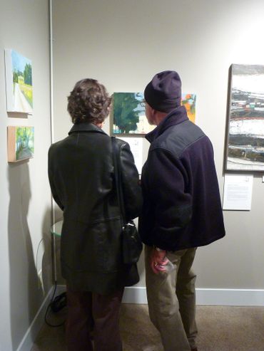 Two people admiring artwork at a Ledbetter Gallery art show.