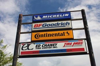 A tall signpost displaying Michelin, BFGoodrich, Continental, and Ed Chaney Tire Pros logos.
