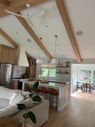 Modern kitchen with wood beams, white ceiling fan, and cozy seating area.