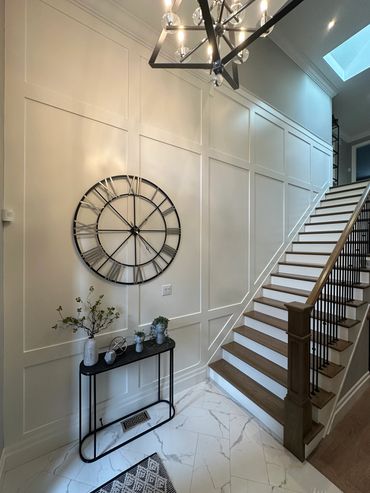 Modern staircase with decorative wall clock and console table.