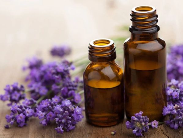 Two amber glass bottles beside blooming lavender flowers on a wooden surface