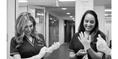 Nurses donning gloves in a hospital setting
