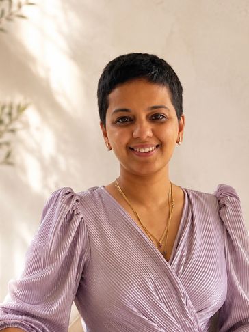Smiling woman with short hair in a lavender dress.
