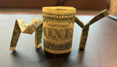 Rolled and folded dollar bills spelling out the word 'MONEY'.
