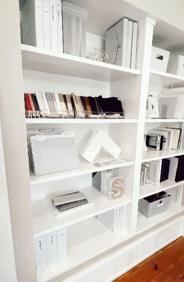 Organized white shelves with books, binders, and decor in a minimalist style.