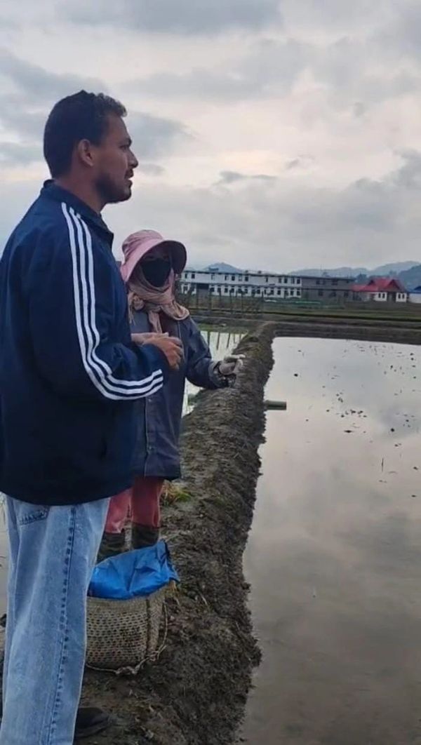 Two people standing by a water-filled field.