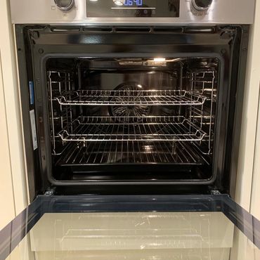 Modern stainless steel oven with open door and interior racks.