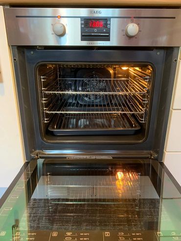 Open AEG oven with racks and a baking tray inside.