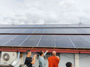 Harness Engineering and China Media observing solar panels on a rooftop at Sitagu Buddhist Academy, Yangon.
