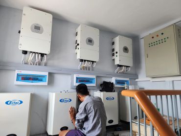 A man working on electrical equipment in a control room.