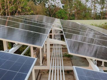Solar panels installed outdoors with greenery in the background.