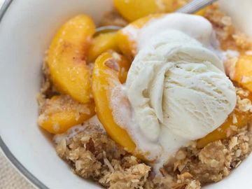 A bowl full of ice cream, peaches, and oats