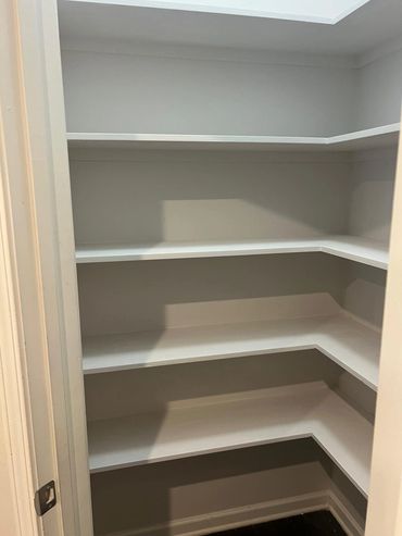 Empty white corner shelves in a small closet space.
