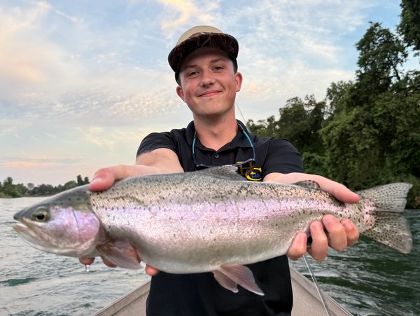 Young man proudly holding a large fish he caught on a boat.