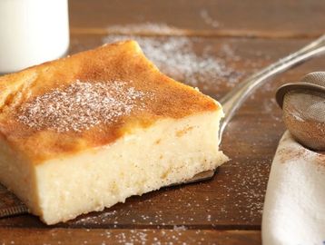 A creamy slice of custard dessert dusted with cinnamon and powdered sugar.