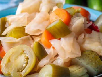 Close-up of mixed pickled vegetables including carrots, cucumbers, and cabbage.