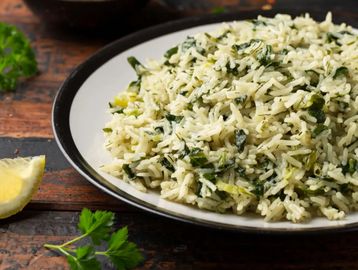 Plate of herb-infused rice with lemon wedge and parsley garnish.