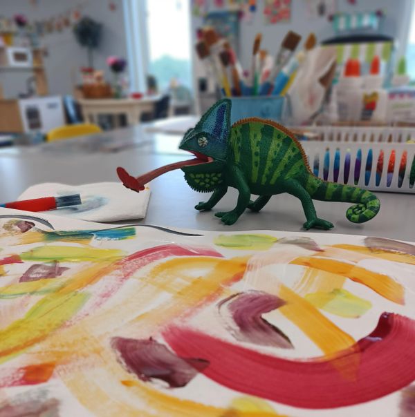 A chameleon toy in front of a painted paper at the ORIGINAL Art Explorers Club in Perkasie PA