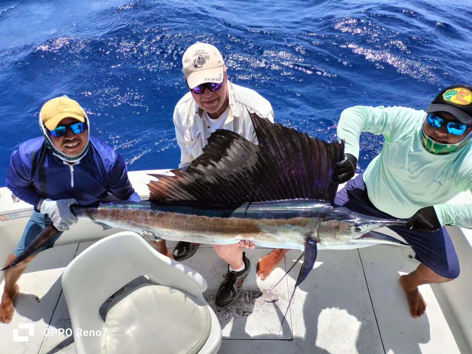 Happy customer and two deck hands holding a Sailfish caught fishing in Cozumel with Cozumel Anglers.