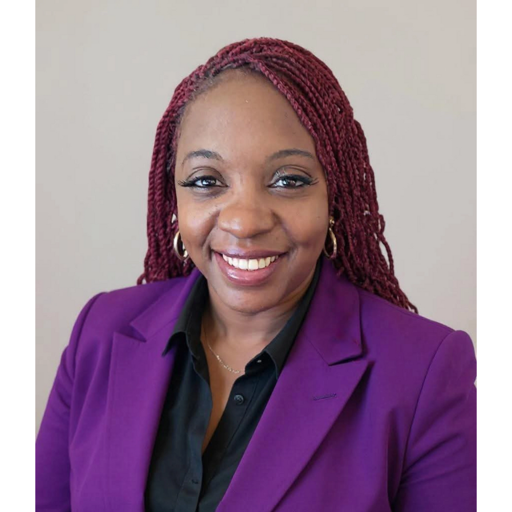 Smiling woman with red braided hair in a purple blazer and black shirt.