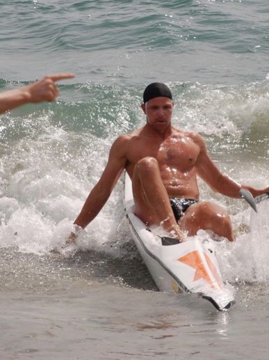 Man paddling a kayak in the ocean near shore.