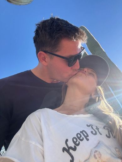 Couple sharing a tender kiss outdoors on a sunny day.