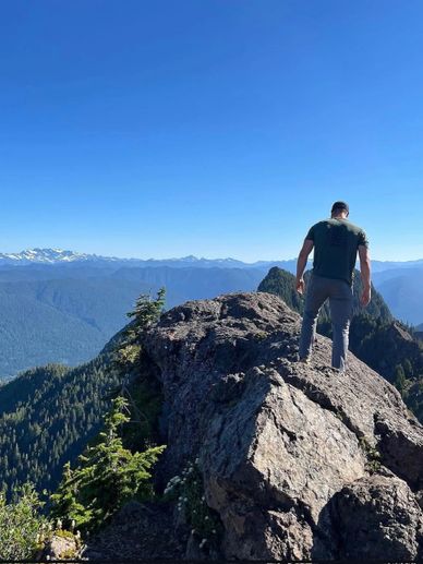 Man standing on rocky mountain peak with clear blue sky.