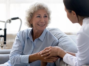Carer offering support to elderly woman
