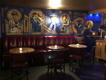 Indoor seating area in the Argyle Cellar Bar in Edinburgh with red seating and Art Deco art painting