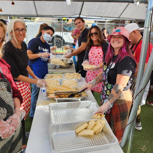 People making tamales together under a tent.