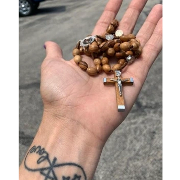 hand holding a rosary with cross and Jesus