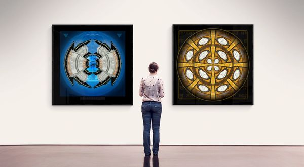 Two banners of mandala style art. One is blue and the other gold in colour in a gallery setting.