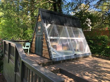 Outdoor A Frame Playhouse for kids with cedar siding on a tiered deck.