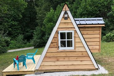 A frame playhouse with deck, cedar siding and metal roof in an Indiana backyard
