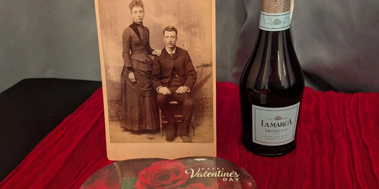 Vintage photo, prosecco bottle, and Valentine's Day heart on a red cloth.