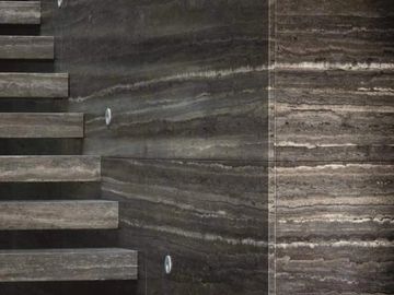 Modern floating stone stairs with dark textured wall.
