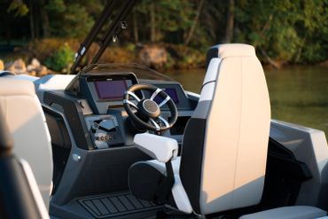 Modern boat cockpit with steering wheel and seats.