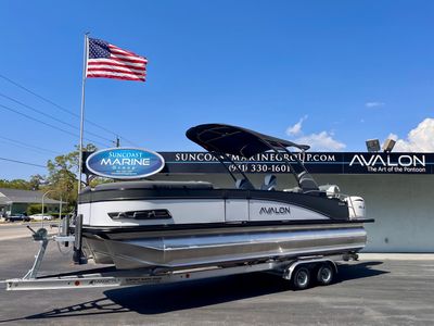 Pontoon boat on a trailer outside a marine dealership.