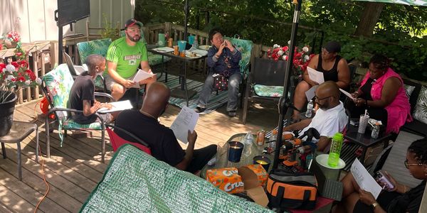 Group meeting outdoors with papers and drinks.