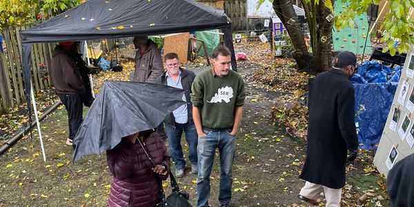 People gathered outdoors with umbrellas and jackets on a rainy day.