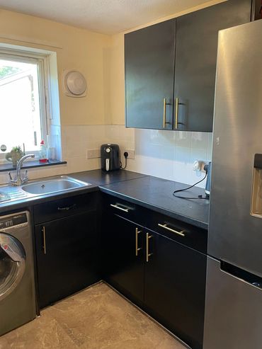 Modern kitchen corner with black cabinets and stainless steel appliances.