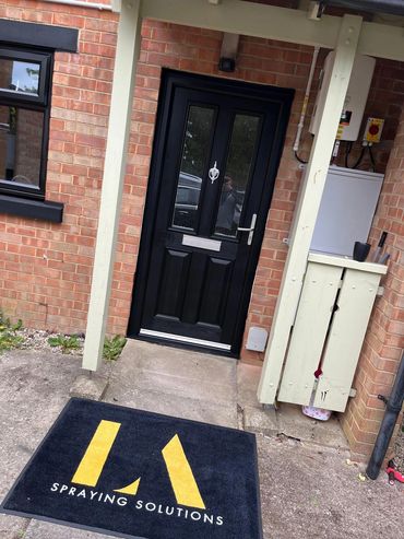 Entrance door with a mat reading 'Spraying Solutions'.