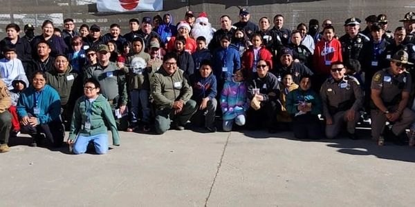 Large group photo of police officers and children outdoors on a sunny day.