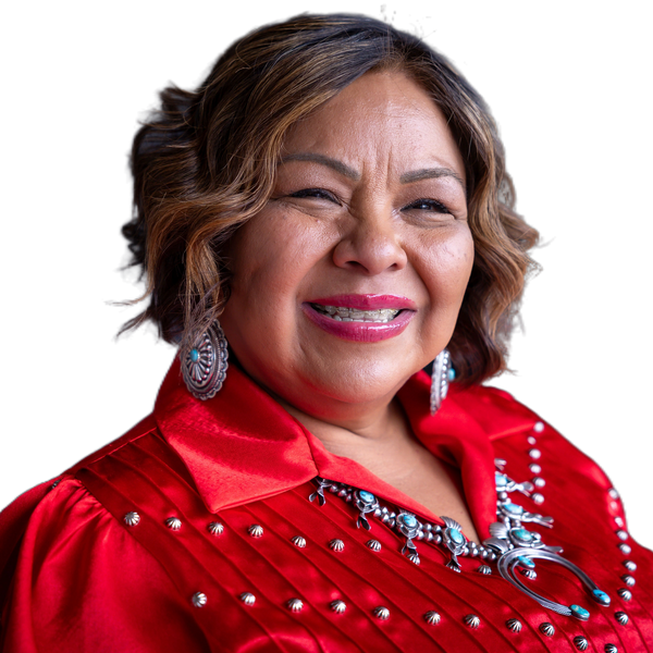 Smiling woman in red traditional outfit with silver and turquoise jewelry.