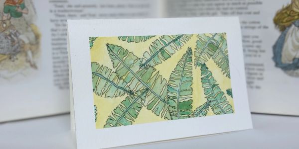 A greeting card with green fern leaves on a yellow background.