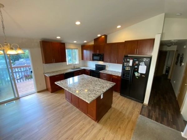 Modern kitchen with granite island and wooden cabinets.