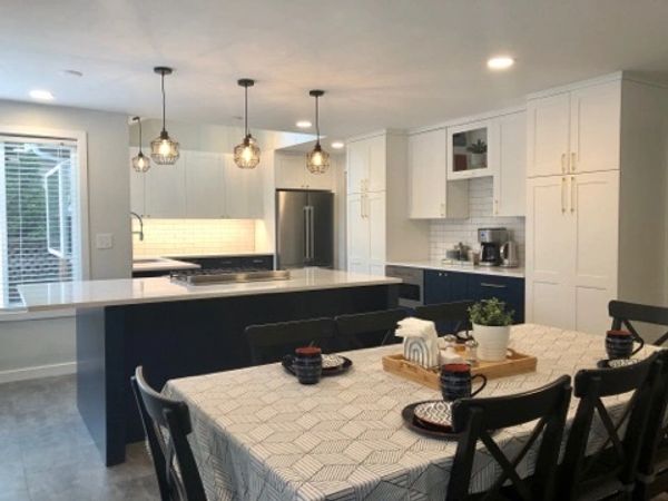 Modern kitchen with white cabinets and a dining table with black chairs.