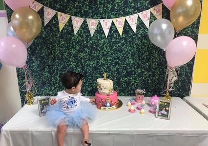 Toddler sits in birthday display with cake