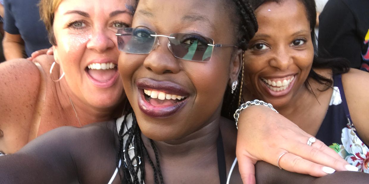 Three women joyfully posing together for a selfie, smiling brightly.